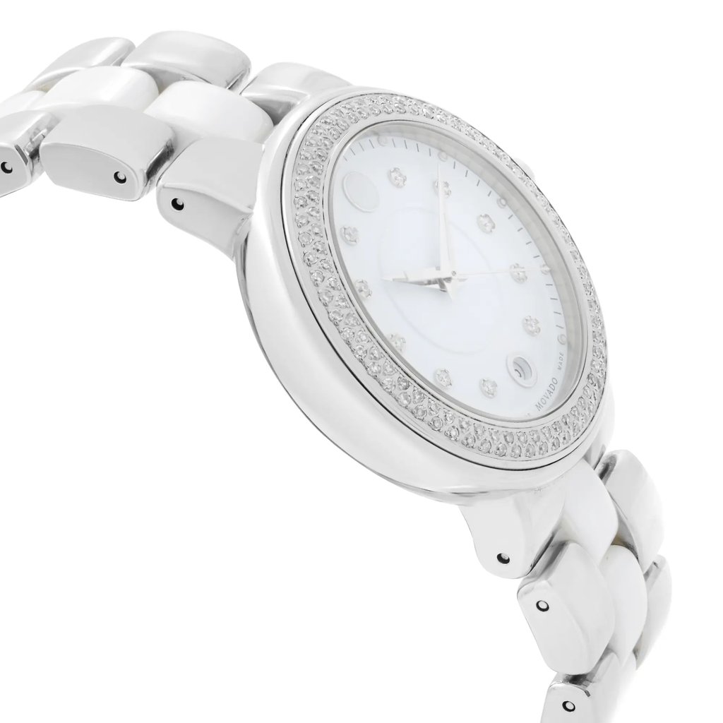 An image of a wristwatch displayed from a side profile view, opposite the crown. The angle showcases the watch at a slight tilt, capturing the sleek, metallic band and the bezel adorned with sparkling stones. The photo is taken at a close distance, highlighting the watch's elegant design and polished finish, typical of a display model.