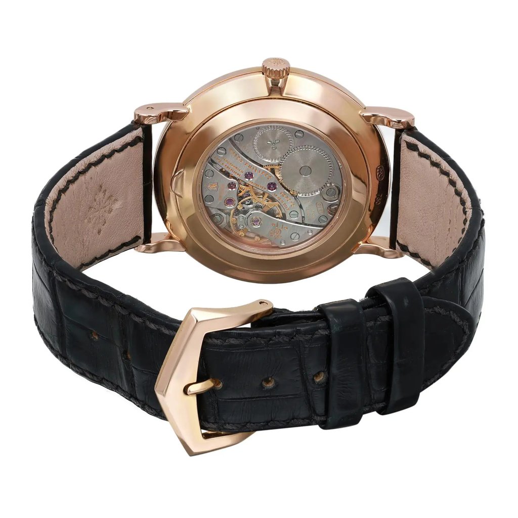 An image of a pre-owned wristwatch showing the back view at a close angle. The focus is on the open clasp and the intricate mechanical workings visible through the transparent case back. The watch has a polished metallic finish and a black leather strap.