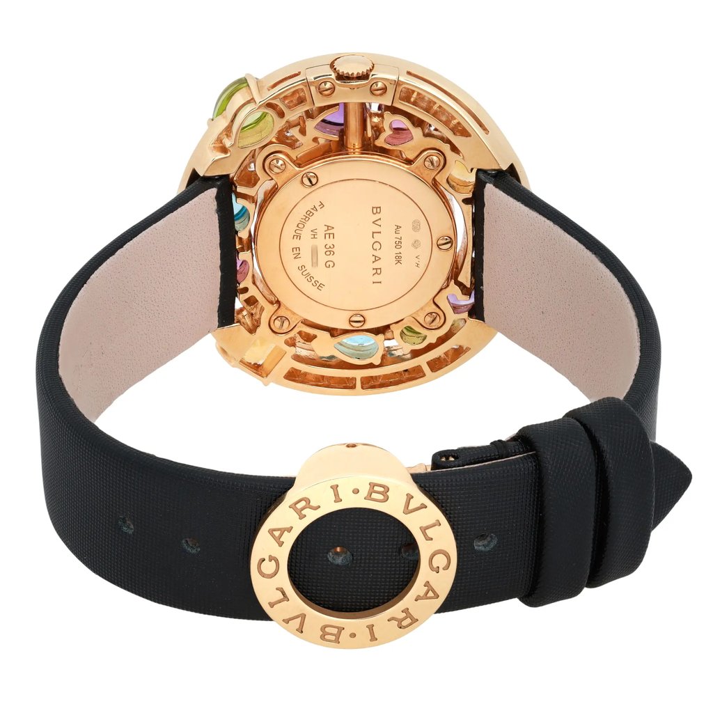 An image of a pre-owned Bvlgari women's wristwatch, shown from a rear angle. The focus is on the watch's back, highlighting the intricate gold casing and colorful accents. The black strap is partially visible, with the brand's name engraved on the clasp. The shot is taken at a close distance, emphasizing the details and craftsmanship.