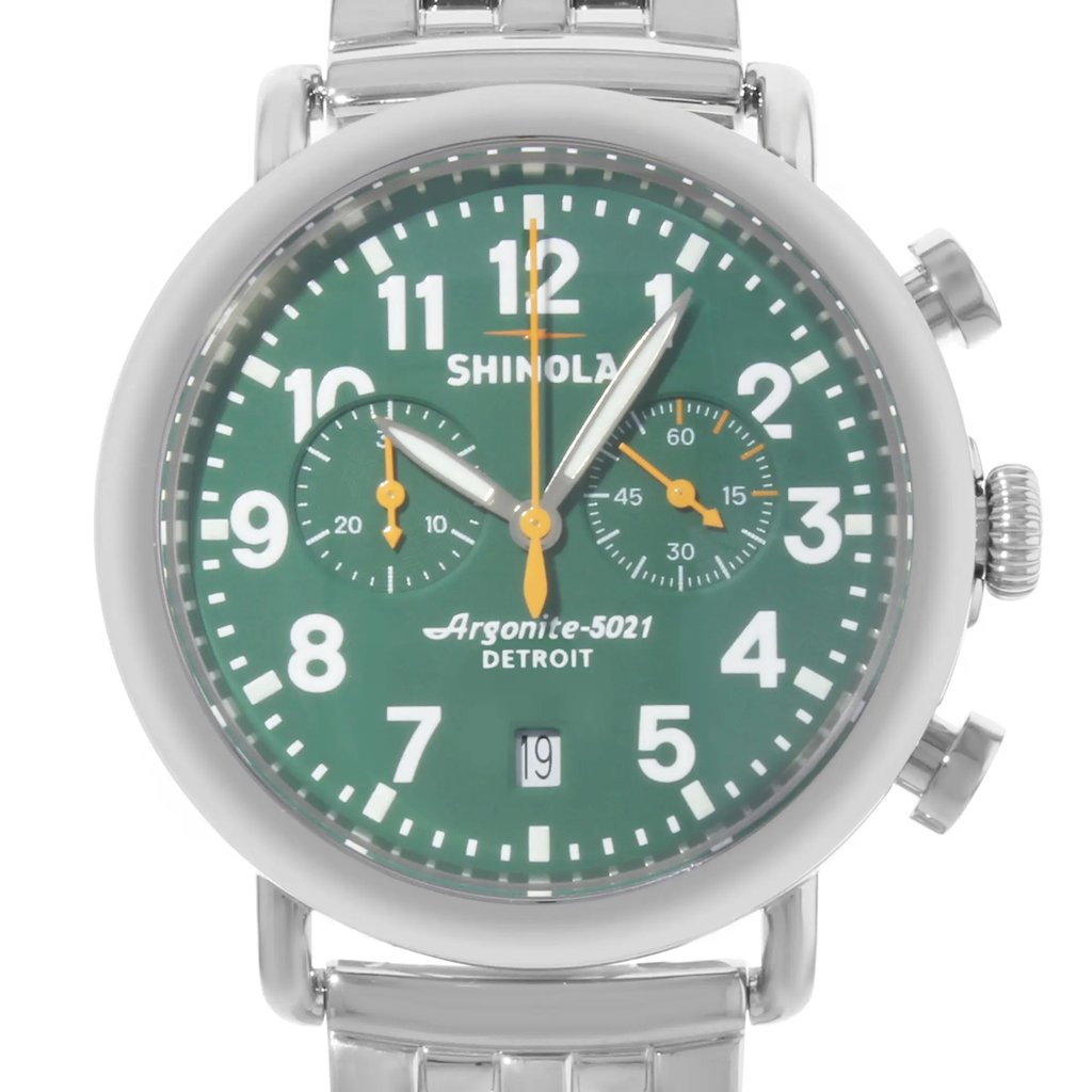 An image of a pre-owned wristwatch shown in a front close-up shot, highlighting the watch face. The watch features a green dial with white numerals and two subdials. The hands are silver with orange accents. The brand name is visible on the dial, and the watch has a date window at the bottom. The silver metal band is partially visible at the top and bottom.