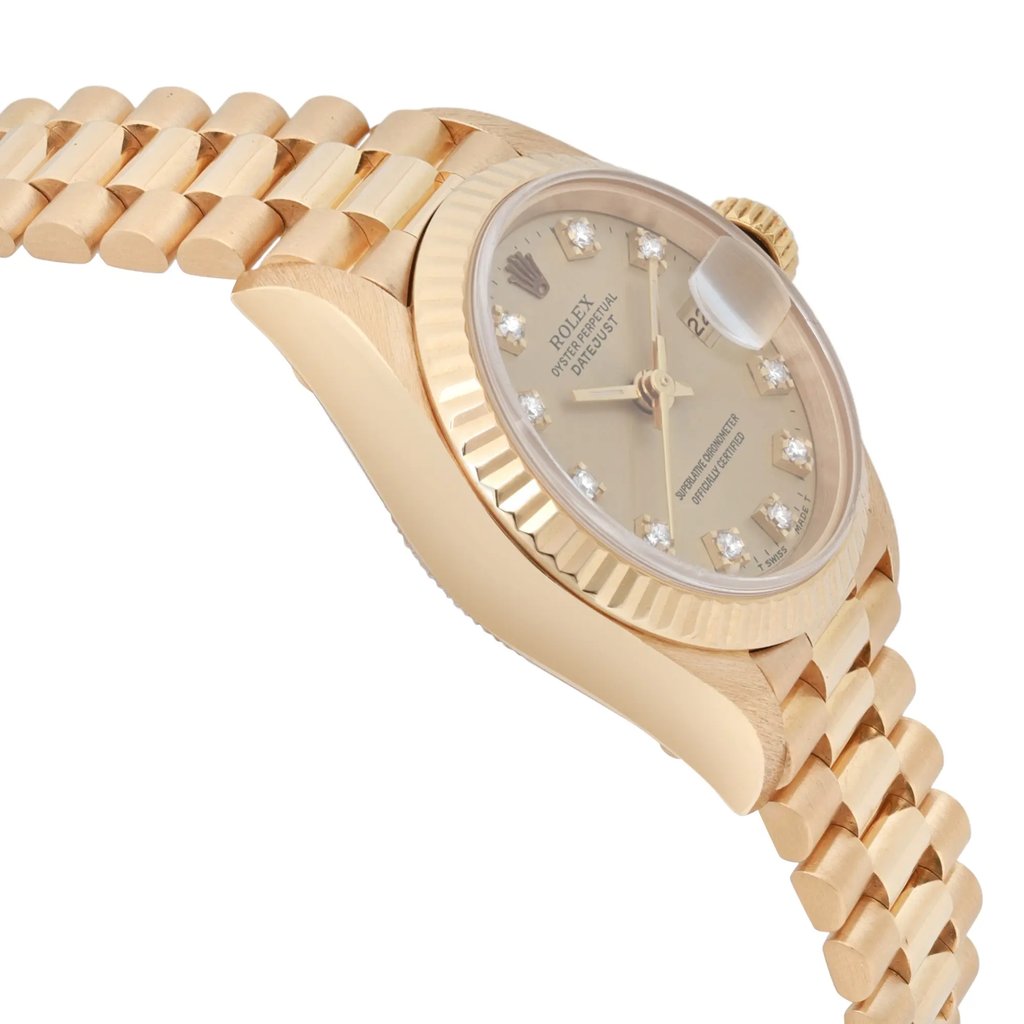 An image of a pre-owned women's Rolex wristwatch taken from a slightly elevated angle, showcasing the left side of the watch. The watch features a yellow gold design with a fluted bezel and a champagne dial adorned with diamond hour markers. The date indicator is visible at the 3 o'clock position, and the luminous hands are clearly displayed. The bracelet is partially visible, showing a series of polished links.