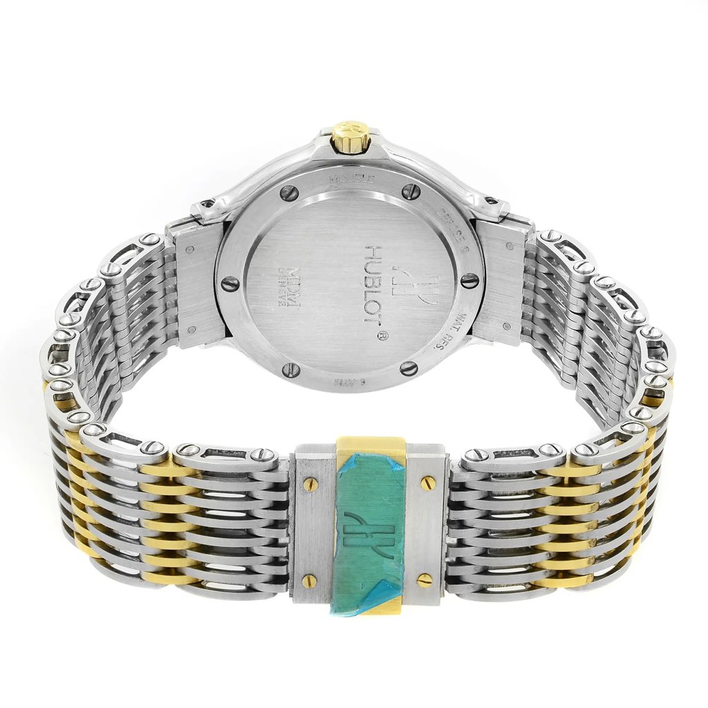 An image of a pre-owned wristwatch, showcasing the back view of the watch case and bracelet. The focus is on the closed clasp, featuring a combination of silver and gold-toned metal links. The watch is positioned upright, with the case back facing the viewer, displaying engraved details. The angle offers a clear, close-up view of the clasp and bracelet design.