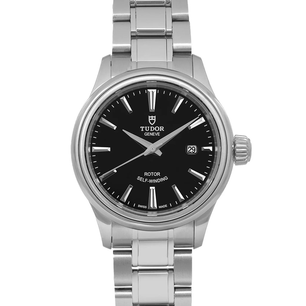 An image of a wristwatch in a front, close-up shot focusing on the watch face. The watch features a black dial with silver hour markers and hands, and a date window at the three o'clock position. The stainless steel case and bracelet are unworn, highlighting the watch's pristine condition.