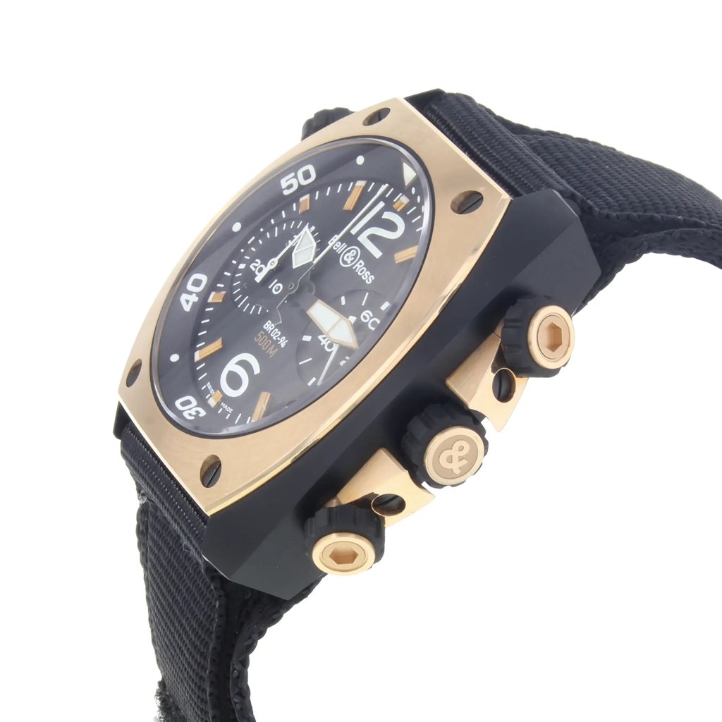 An image of a Bell & Ross men's wristwatch, displayed from a side profile angle with the crown visible. The watch features a luxury diver style with a black dial and rose gold bezel. It has a tonneau-shaped stainless steel case and is fitted with a black fabric/canvas band. The watch appears as a display model, positioned close-up, with its details and textures clearly visible.