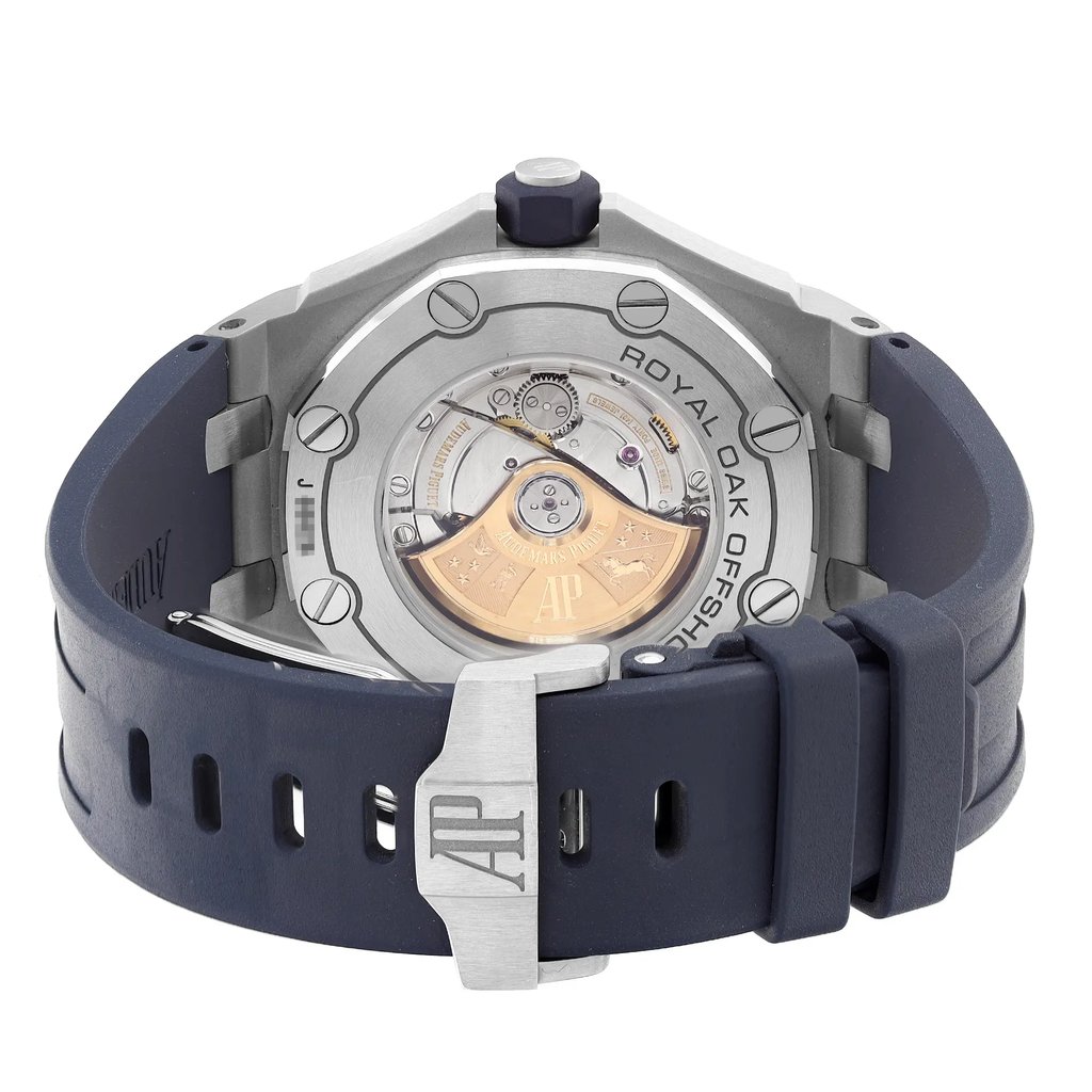 An image of a pre-owned wristwatch, viewed from the back at a close angle. The focus is on the clasp and visible watch mechanism. The watch features a metallic case with visible screws and a dark blue strap. The branding is subtly engraved on the clasp and around the mechanism, offering a detailed view of the watch's intricate inner workings.
