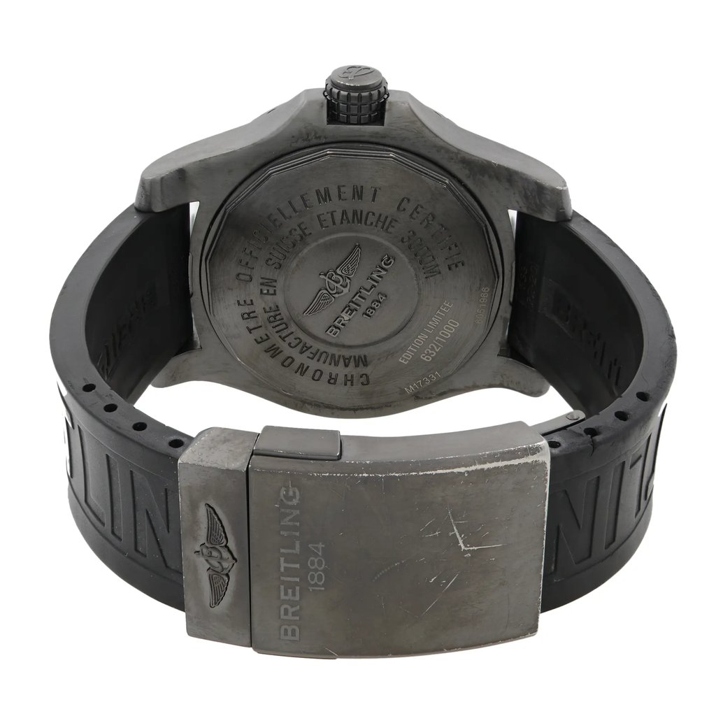 An image of a pre-owned Breitling men's wristwatch showcasing the back view with a closed clasp. The watch features a screwback stainless steel caseback with engraved details, paired with a black rubber band. The round shape of the watch is visible, and the image is taken from a top-down angle, with the watch centered and occupying most of the frame for a clear and detailed view.