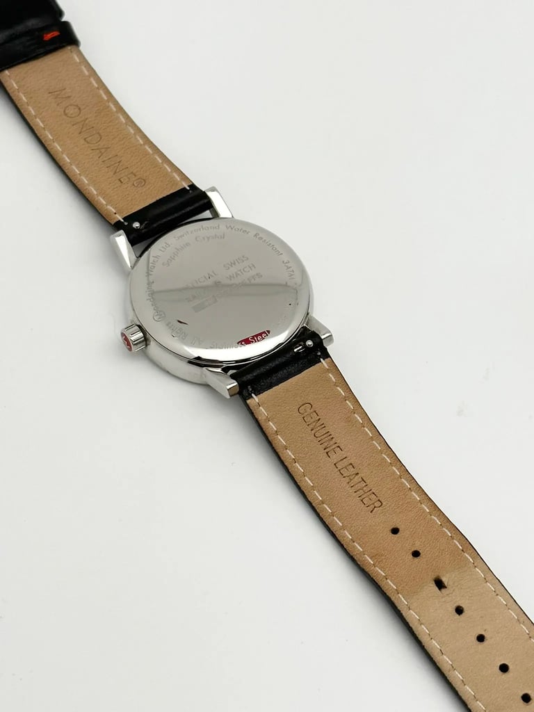 An image of a Wristwatch by Mondaine. This Pre Owned item is designed for Unisex Adult, featuring a Casual style. It has a Quartz movement and an Analog display with a White dial color. The indices include 12-Hour Dial,Stick Indexes. The band is made of Leather and the case is made of Stainless Steel. The watch has a Round shape with a case size of 35 mm and a case thickness of 9 mm.