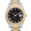 An image of a pre-owned Rolex men's wristwatch, presented in a front close-up view highlighting the watch face. The luxurious round dial is black with gold Roman numeral indices and a date indicator at the 3 o'clock position. The watch has a fluted gold bezel and a band made of stainless steel and solid gold. The condition is good with light signs of wear or scratches. The watch is at a close distance, with the face centered and positioned frontally to the viewer.