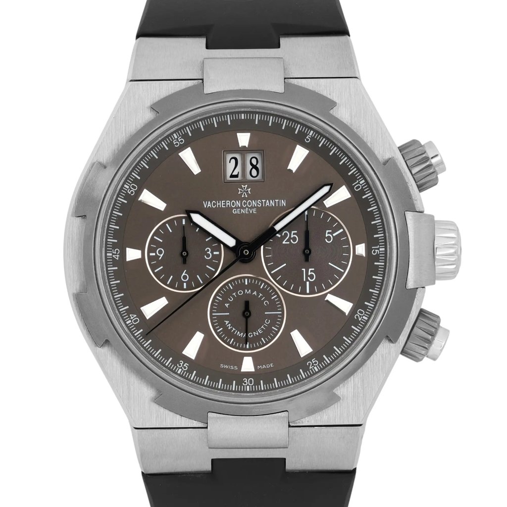 An image of a pre-owned men's Vacheron Constantin wristwatch, viewed from a straight-on angle at a close distance. The watch features a round silver case, a grey dial with luminous hands, and a date indicator at the top. It also has three sub-dials for additional functionality. The crown and pushers are visible on the right side, and the watch is attached to a black strap.