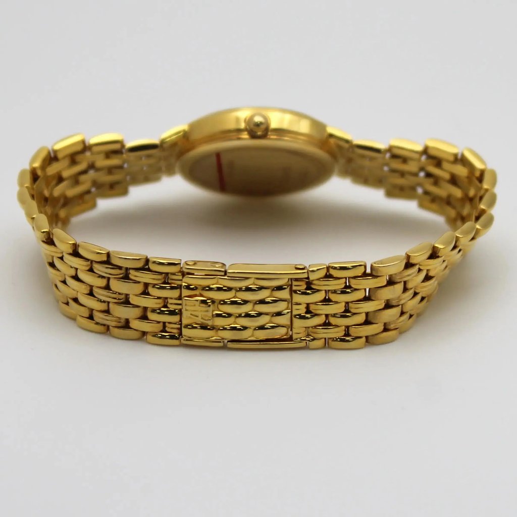 An image of a pre-owned Audemars Piguet women's wristwatch. The watch is positioned horizontally on a neutral background, with the focus on its yellow gold bracelet. The angle is from the rear, showcasing the intricate link design and clasp. The watch face is slightly blurred, emphasizing the bracelet's polished finish. The photo is taken at a close distance, capturing the detailed craftsmanship.