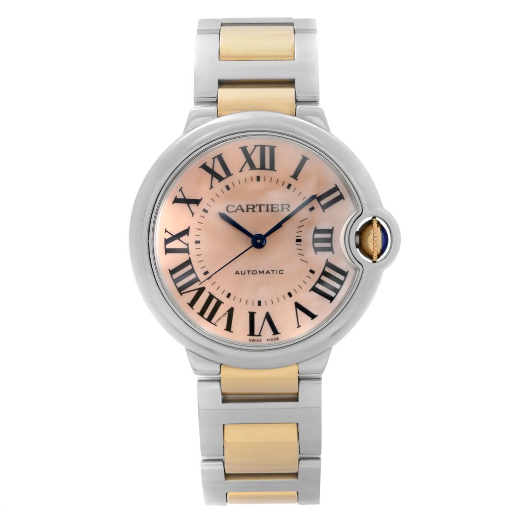 An image of a pre-owned wristwatch displayed from a front full frontal view. The watch features a round face with a pink dial and Roman numeral hour markers. It has a metallic bezel and a two-tone metal bracelet strap. The watch crown is visible on the right side, adorned with a blue cabochon. The brand name is visible on the watch face.