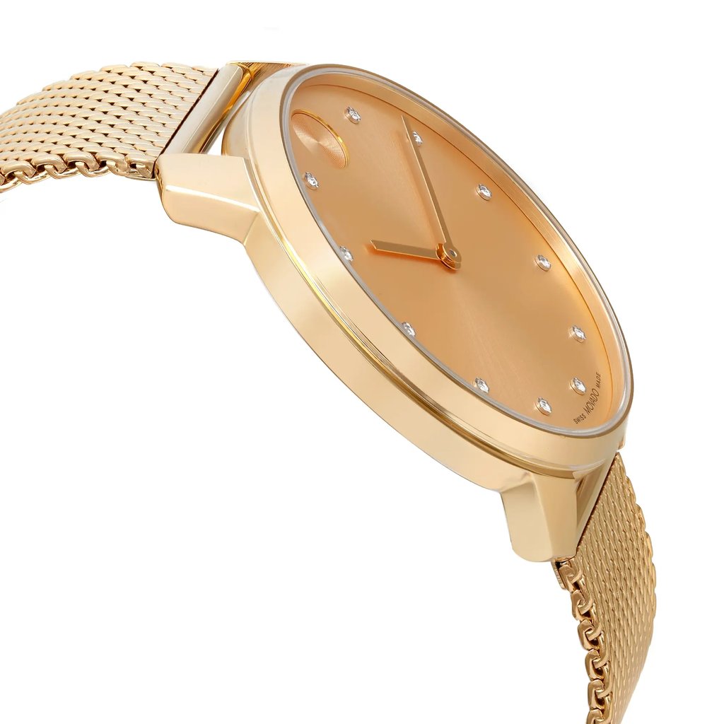 An image of a pre-owned wristwatch captured from a side profile view opposite the crown. The watch features a gold-toned case and a matching mesh band. The face is also gold-toned, with minimalist hour markers and simple hands. The angle highlights the sleek design and the distance emphasizes the watch's elegant details.