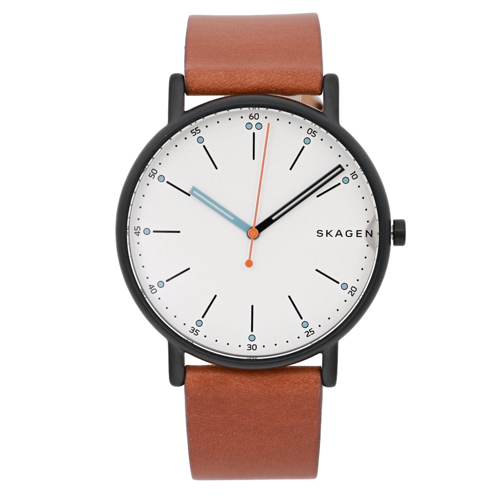 An image of a Skagen men's wristwatch taken from a straight-on angle, positioned centrally in the frame. The watch features a black case with a white dial, showcasing luminous hands in blue and orange. Black hour markers and dots accent the minimalist design. The brown leather strap is visible at the top and bottom, emphasizing the watch's sleek and modern appearance.