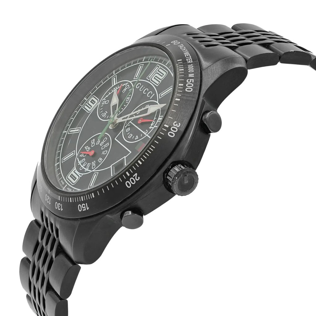 An image of a pre-owned Gucci men's wristwatch in a dress/formal style, presented in a side profile view with the crown visible on the right side. The watch features a round stainless steel case and band, both colored black. The dial is black with luminous hands, chronograph features, and a small seconds subdial. The bezel is also black and includes tachymeter markings. The watch is positioned at a slight angle to the camera, allowing a clear view of the dial's details and the side profile including the crown and pushers, with a medium-close distance emphasizing the timepiece's design and features.