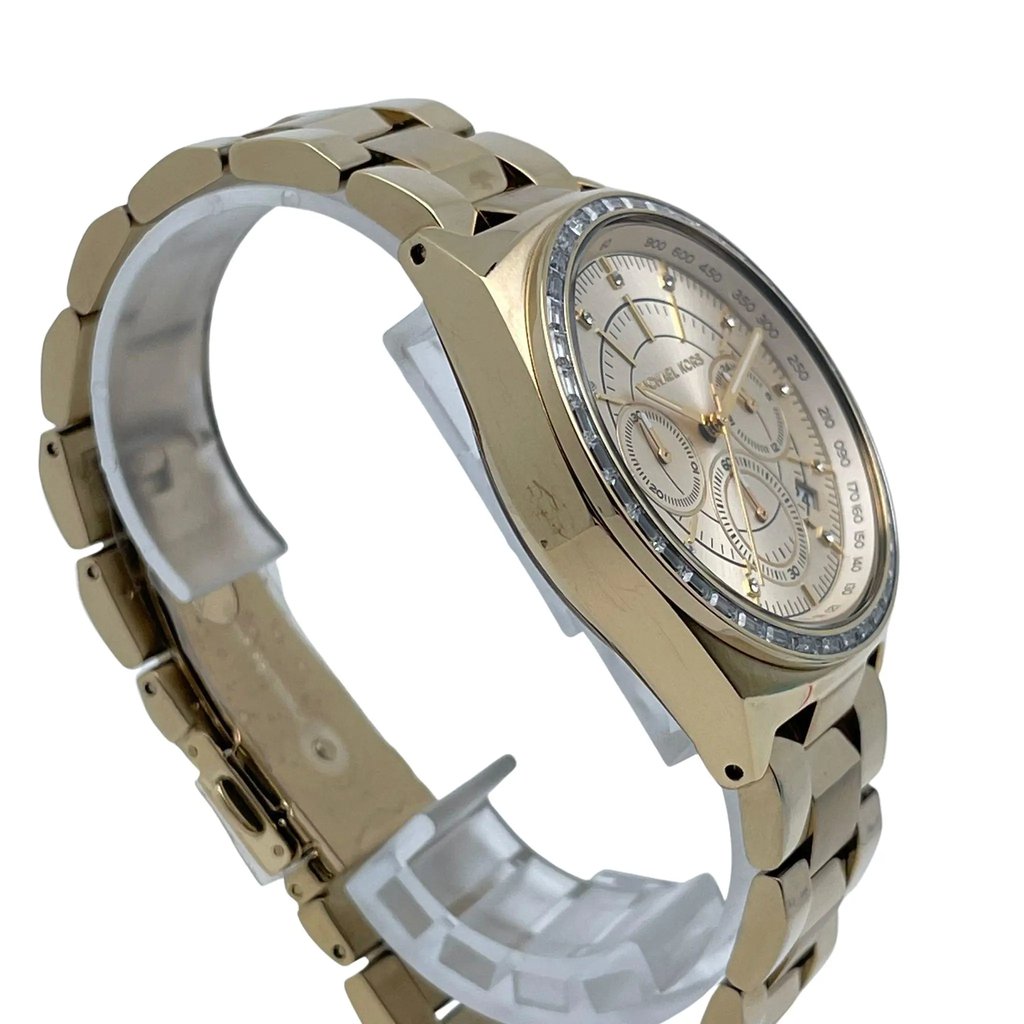 An image of a Wristwatch by Michael Kors. This Pre Owned item is designed for Women, featuring a Casual,Dress/Formal style. It has a Quartz movement and an Analog display with a Champagne dial color. The indices include 12-Hour Dial,Non-Numeric Hour Marks. The band is made of Stainless Steel and the case is made of Stainless Steel. The watch has a Round shape with a case size of 39 mm and a case thickness of 10 mm.