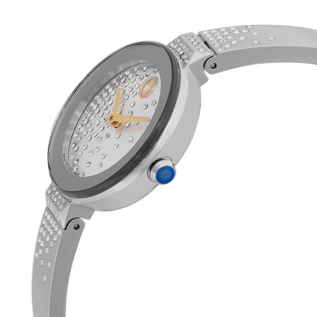 An image of a pre-owned wristwatch taken from a side profile view. The focus is on the watch's crown, which is prominently visible. The watch features a sleek metal band embellished with small, sparkling stones. The dial has gold-tone hands and a textured surface with a circular pattern. The angle highlights the watch's elegant design and the intricate detailing on the band, captured at a close distance.