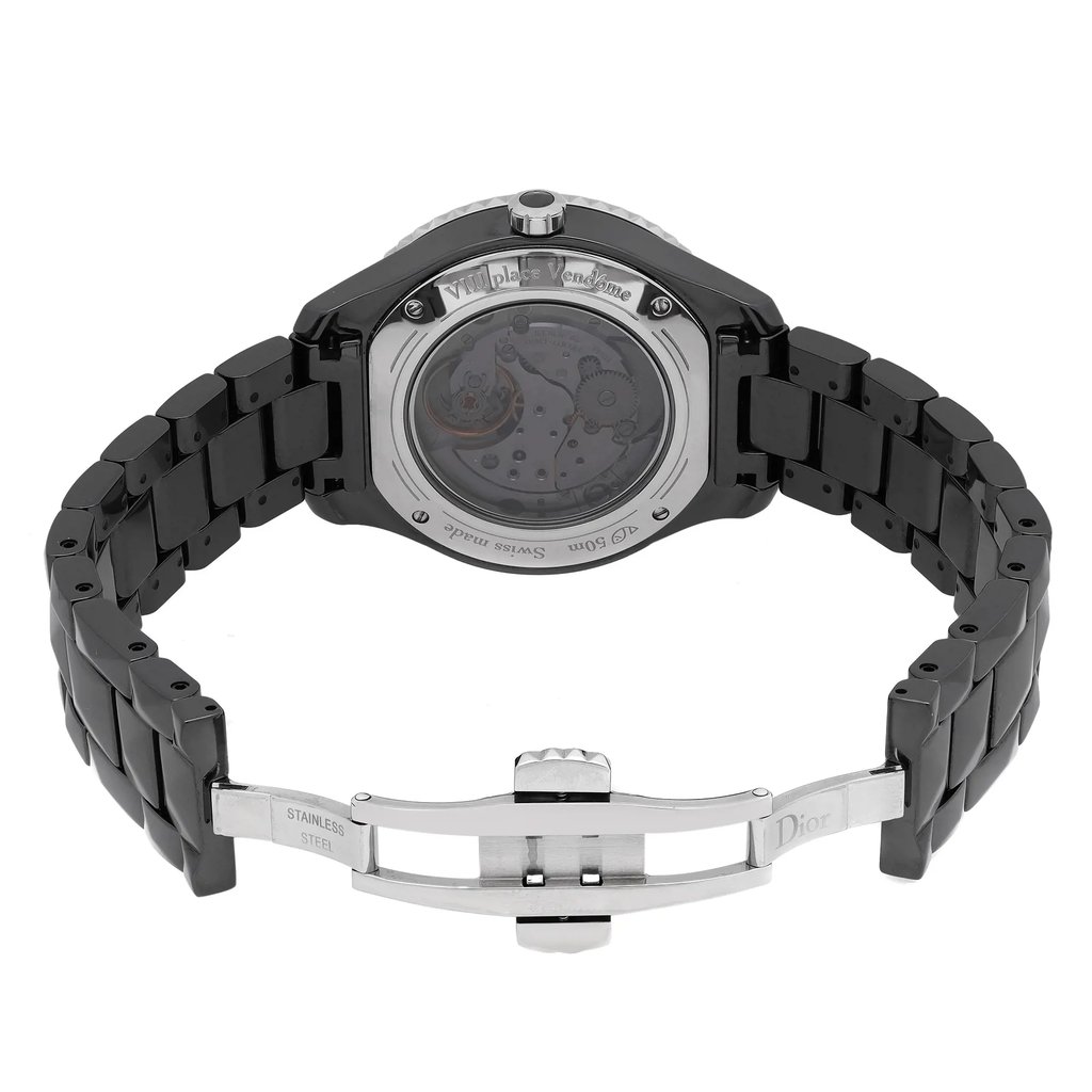 An image of a wristwatch from a back view, showcasing its open clasp. The watch is positioned horizontally, with the camera capturing it at a slight angle from above, highlighting the intricate details of the exposed mechanism through a transparent case back. The black metal bracelet is partially extended, displaying the stainless steel clasp engraved with "Dior." The overall appearance is sleek and polished, indicative of a display model.