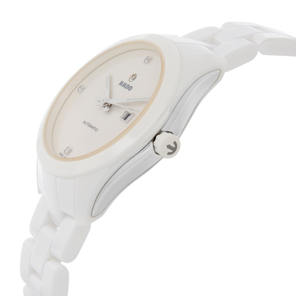 An image of a wristwatch shown from a side profile view, focusing on the crown. The watch has a white band and a light-colored dial. The crown is prominently visible on the right side, and the watch is positioned at an angle that showcases its sleek design. The photograph is taken at a close-up distance, highlighting the watch's details and craftsmanship.