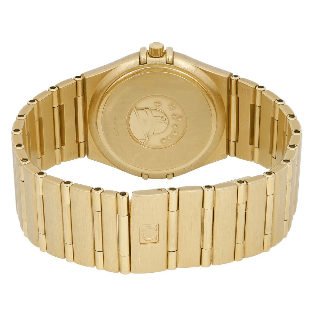 An image of a pre-owned wristwatch, focusing on the back view with a closed clasp. The watch is positioned horizontally, showcasing the engraved case back and the linked metal bracelet. The angle is straight-on, capturing the details of the clasp and the watch's finish from a close distance. The watch has a gold-tone appearance.