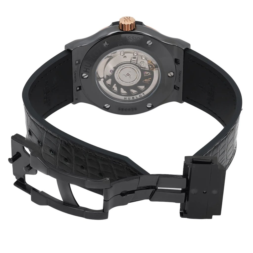 An image of a pre-owned men's Hublot wristwatch viewed from the back at a slight angle, showcasing the open case back and mechanical movement. The watch is positioned upright with its black, textured strap partially open, displaying the clasp and inner leather pattern. The crown is visible at the top, and the photograph is taken from a close distance, emphasizing the watch's details and craftsmanship.
