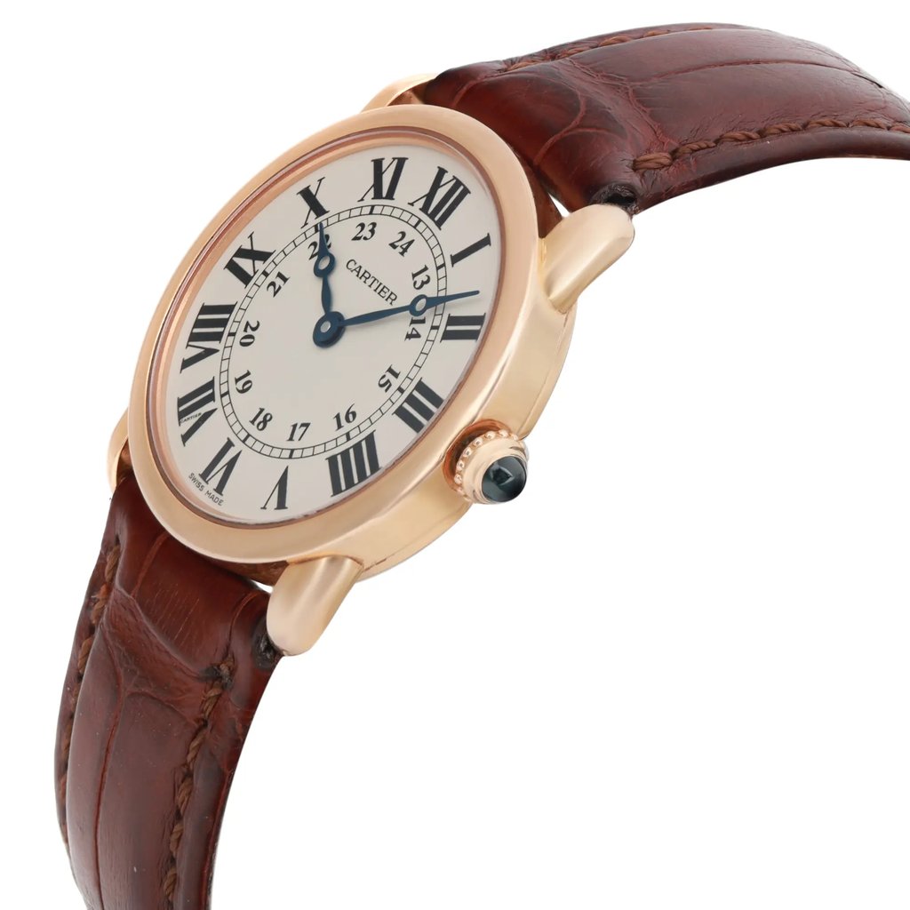 An image of a pre-owned wristwatch shown from a side profile view, highlighting the crown. The watch features a gold-toned case and a brown leather strap, with the face displaying Roman numeral hour markers and blue hands. The angle provides a clear view of the watch's elegant design, emphasizing its classic style.