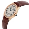 An image of a pre-owned wristwatch shown from a side profile view, highlighting the crown. The watch features a gold-toned case and a brown leather strap, with the face displaying Roman numeral hour markers and blue hands. The angle provides a clear view of the watch's elegant design, emphasizing its classic style.