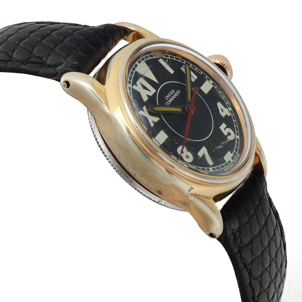 An image of a pre-owned women's Rolex wristwatch positioned at a slight angle from the left side, showcasing the watch face and part of the band. The watch has a gold-toned case and a black leather strap with a textured pattern. The dial is black with large contrasting numerals and a red second hand. The shot is taken at a close distance, emphasizing the details of the watch's design and condition.