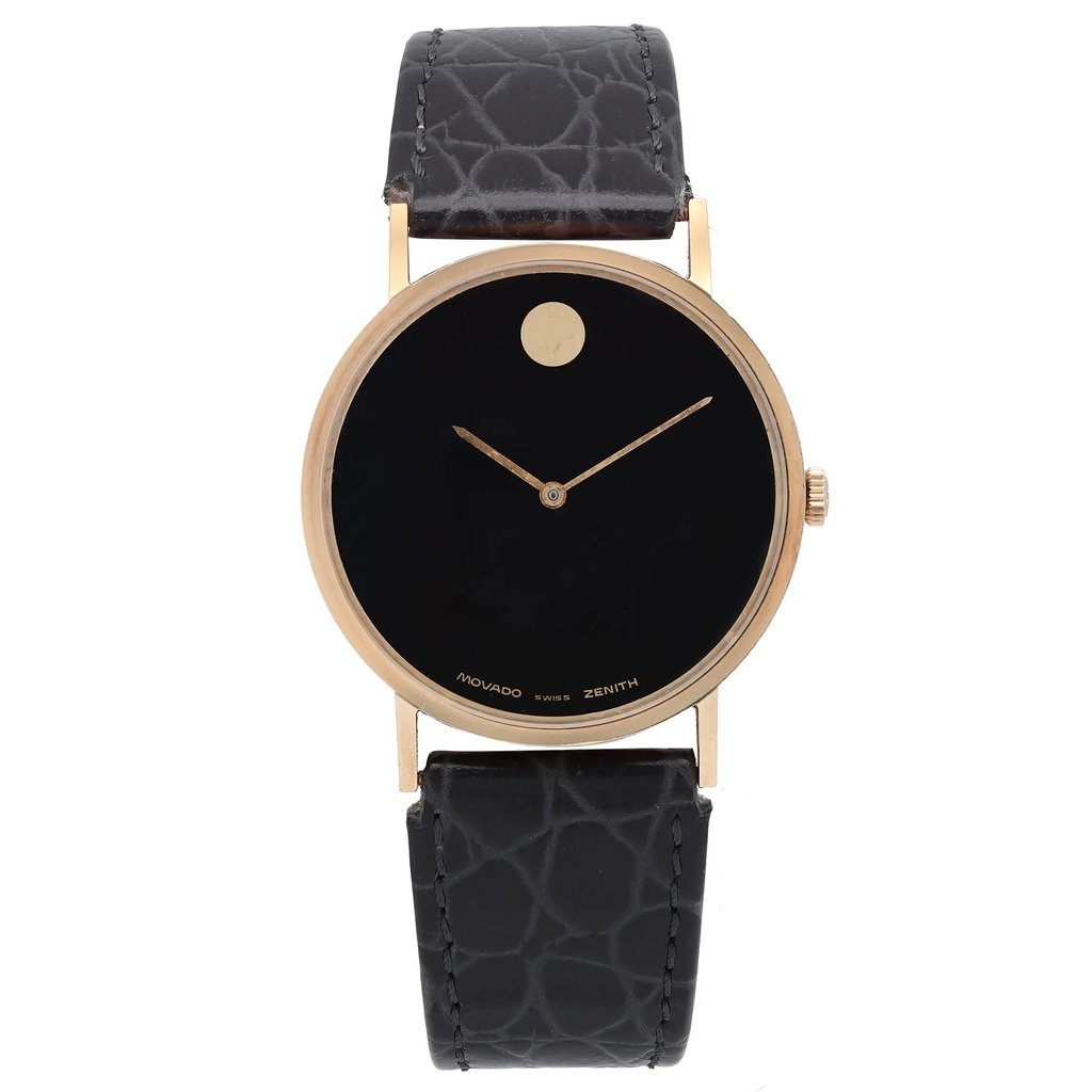 An image of a pre-owned wristwatch captured from a front full-frontal view. The watch features a round black dial with minimalist design elements and a gold-toned case. The strap is textured black leather, and the brand name appears subtly on the dial. The image is taken from a close distance, emphasizing the watch's sleek and elegant design.