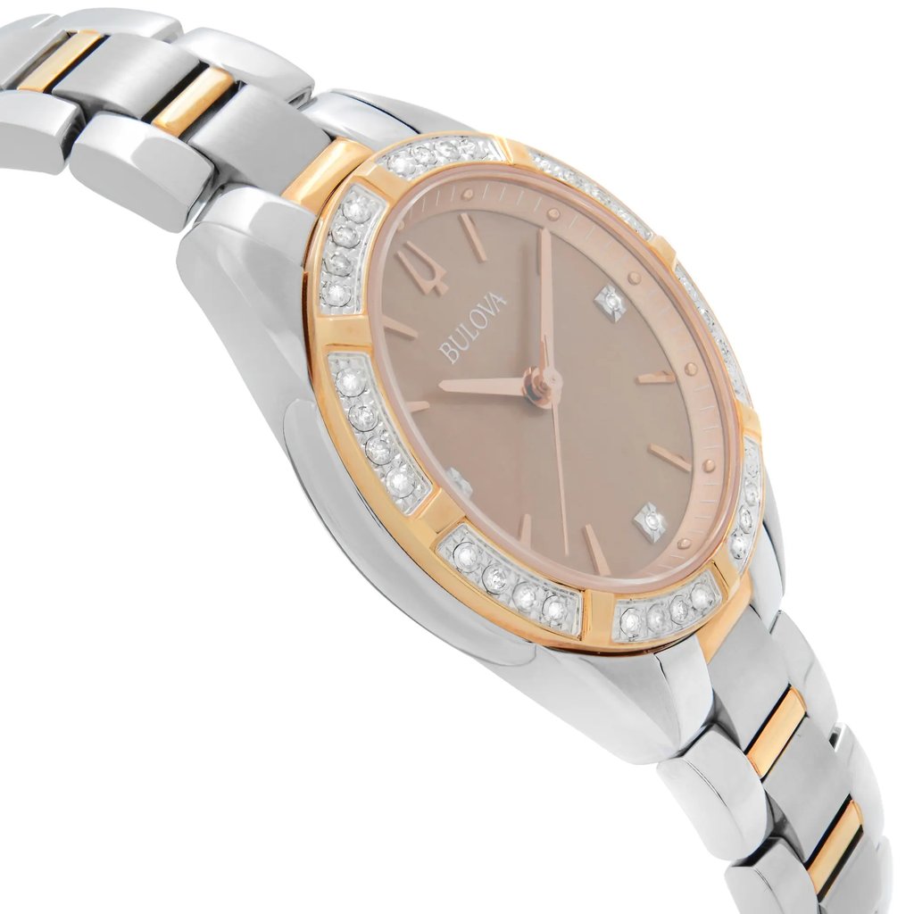 An image of a new Bulova women's wristwatch with defects, presented in a side profile view opposite the crown. The watch features a round shape with a bronze dial that has a mother of pearl pattern. It has a rose gold-tone bezel embellished with diamonds and is attached to a two-tone stainless steel band. The overall style is dress/formal. The watch is captured from a close distance, focusing on the side and face of the watch to highlight its design and the contrasting colors of the band.