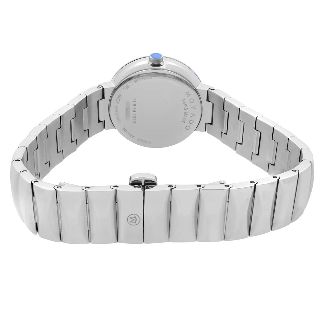 An image of a wristwatch highlighting the back view, focusing on the closed clasp. The watch is positioned upright, displaying its metallic bracelet and the circular back of the watch face. The angle is slightly elevated, capturing the seamless design of the clasp and the engraved details on the back. The photo is taken at a close distance, emphasizing the watch's polished finish and intricate link design.