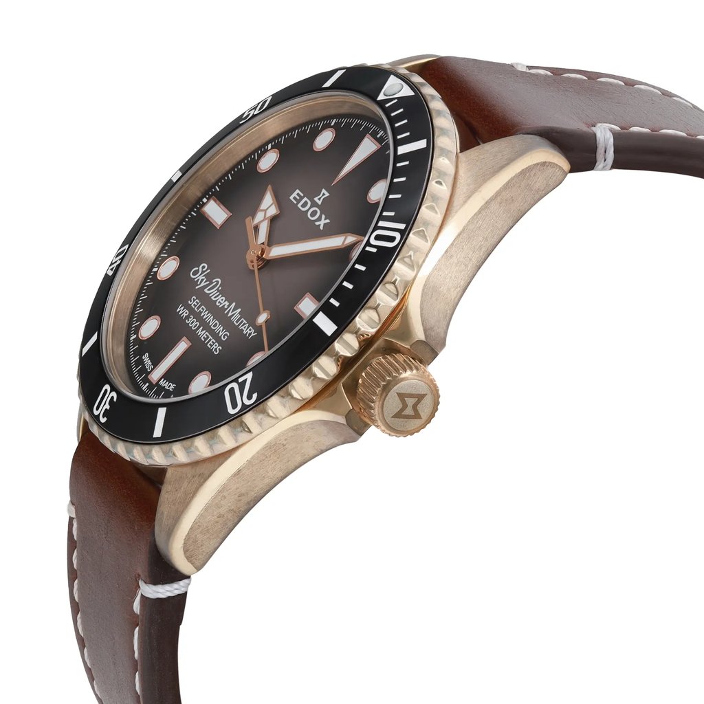 An image of a pre-owned wristwatch viewed from the side profile, showcasing the crown prominently. The watch face is angled slightly upward, revealing the brand name and details on the dial. The leather strap is visible, extending from the watch case. The image captures the watch in close-up, highlighting the design and details.