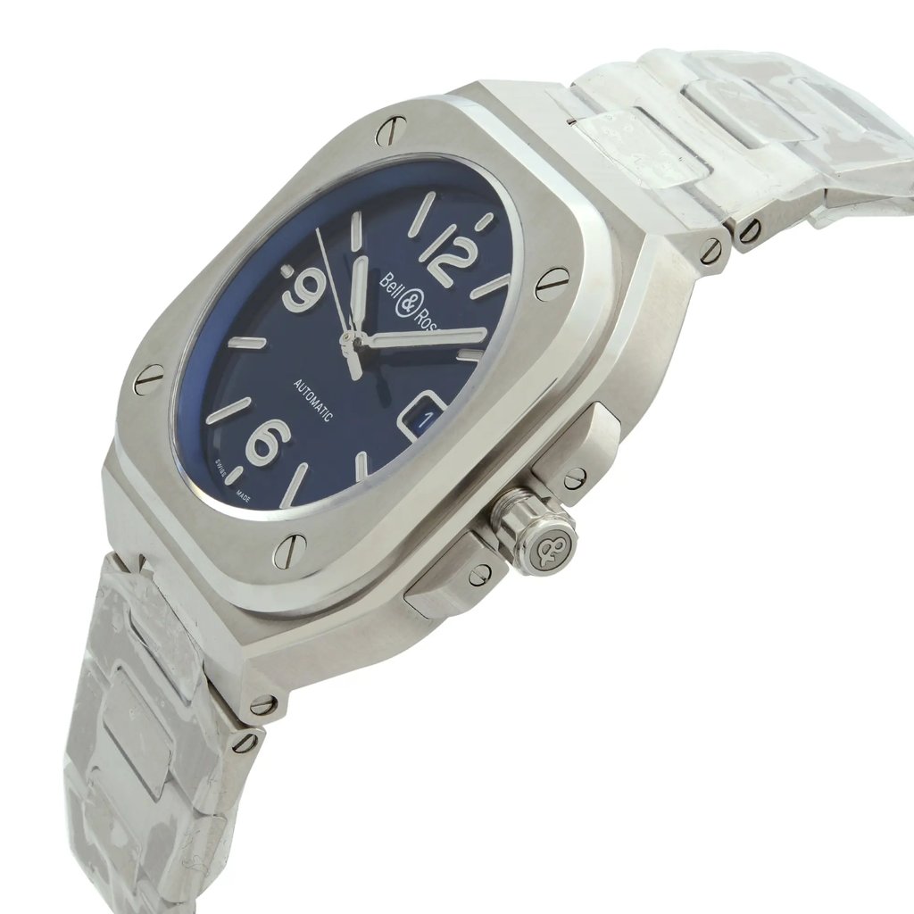 An image of a Bell & Ross men's wristwatch in a display model condition, showcasing a side profile view with the crown visible. The watch features a cushion shape, a blue dial, and is constructed with a stainless steel case and band, presenting a dress/formal luxury style. The photo is taken from a close distance, emphasizing the watch's side angle to highlight the crown and the band's details.