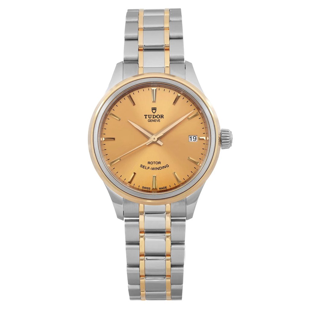 An image of an unworn wristwatch taken from a front full frontal view. The watch features a two-tone metal bracelet with both silver and gold links. The dial is a warm gold color, displaying the brand name and a date window on the right. The watch is positioned centrally with the face clearly visible, showcasing its sleek and elegant design.