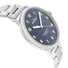 An image of a wristwatch taken from a side profile view opposite the crown, showcasing its sleek design. The watch features a metallic bracelet and a dark blue face with white and yellow markers. The watch is positioned at a slight angle, emphasizing the thickness of the case and the polished links of the bracelet.