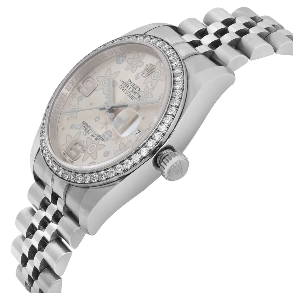 An image of a pre-owned women's Rolex wristwatch, featuring a side-angle view. The watch is positioned with the face slightly tilted upward, showcasing its date indicator and luminous hands. The bezel is adorned with a circle of sparkling stones, and the silver metal bracelet is visible, extending diagonally across the image.