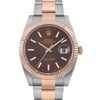 An image of a pre-owned men's Rolex wristwatch taken from a front-facing angle. The watch features a brown dial with luminous hands and a date indicator. The bezel and center links of the bracelet are in rose gold, while the outer links are in stainless steel. The photograph is taken at a close distance, highlighting the intricate details of the watch face and bracelet.