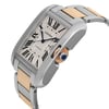 An image of a pre-owned women's Cartier wristwatch featuring a date indicator. The watch is shown from a slightly elevated angle, highlighting its rectangular face with Roman numerals and a two-tone metal bracelet. The focus is on the side of the watch, capturing the crown adorned with a blue gem, from a close-up distance.