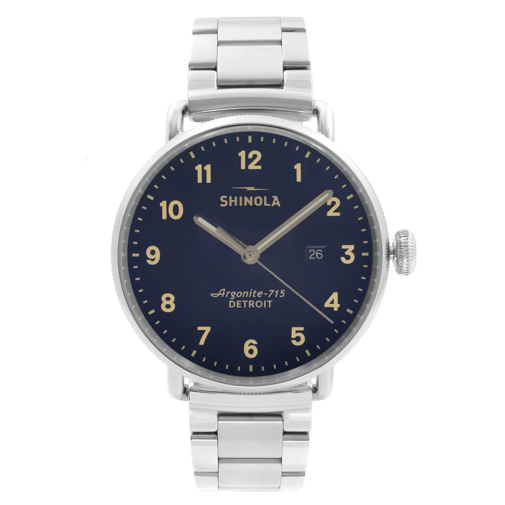 An image of a wristwatch shown from a front full frontal view. The watch features a silver metal strap and a dark blue dial with beige numerals and hands. The brand name is visible on the face, along with the model details. The watch is positioned centrally in the image, displaying its condition as a display model.