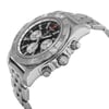 An image of a pre-owned Breitling men's wristwatch in a luxury style, captured from a side profile angle with the crown visible. The watch features a round stainless steel case and band, a gray bezel, and a black dial with luminous hands, a date indicator, GMT, and a small seconds subdial. The image is taken from a close highlighting light signs of wear such as minor scratches. The perspective is slightly tilted, showcasing the watch's design and features.