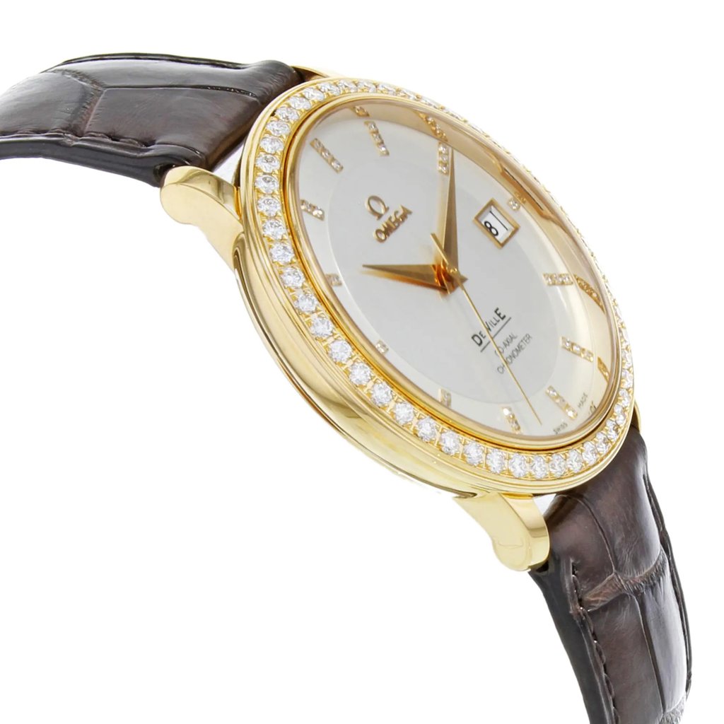 An image of a men's OMEGA wristwatch, captured from a slightly elevated angle at a close distance. The watch features a rose gold case adorned with a ring of diamonds around the bezel. The face is white with gold hour markers and hands, along with a date display. The watch is attached to a dark brown leather strap, visible in the background.