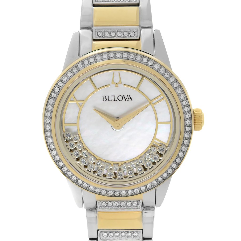 An image of a front close-up view of a display model Bulova women's wristwatch. The watch face is round with a white mother of pearl dial pattern, gold-tone hands, and the Bulova logo at the top. It features Roman numerals and stick indexes for the 12-hour dial. The bezel is gold-tone, encrusted with clear diamonds. The band is made of gold-plated stainless steel with a central gold strip flanked by silver-tone links. The watch is photographed head-on, with the watch face centrally positioned and fully visible, showcasing the design details and the blend of colors and materials.