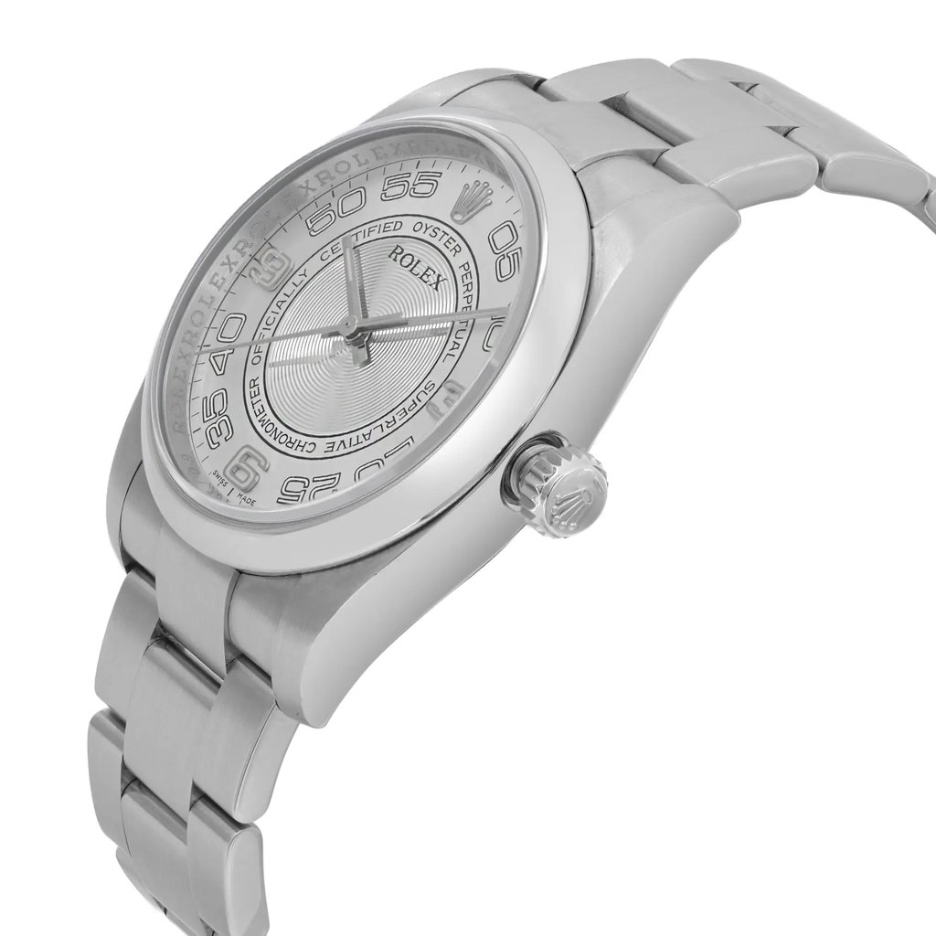 An image of a pre-owned wristwatch shown from a side profile view, highlighting the detailed crown. The angle captures the sleek design of the watch case and the metallic bracelet, which is partially visible. The image is taken at a close distance, showcasing the intricate details and craftsmanship of the watch face and links.