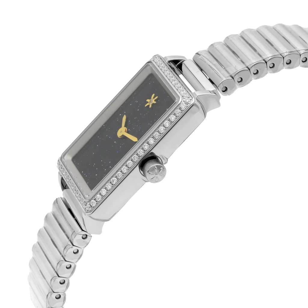 An image of a wristwatch shown in a side profile view, highlighting the crown on the right side. The watch features a rectangular face with a dark dial and gold hands, accented by a bezel adorned with small stones. The unworn metallic bracelet is visible, showcasing a series of linked segments. The angle and distance provide a clear view of the watch's elegant design and details.