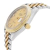 An image of a pre-owned Rolex men's wristwatch, captured from a side profile angle showcasing the crown. The watch features a round shape with a champagne dial and gold bezel. The band is made from a combination of stainless steel and solid gold, presenting a two-tone appearance. Visible features include a date indicator at the 3 o'clock position and luminous hands. There are minor signs of wear and scratches on the watch, consistent with its pre-owned condition. The image is taken from a close distance, emphasizing the watch's luxury style and details.