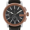 An image of a pre-owned Gucci men's wristwatch in good condition. The photograph is a front close-up shot of the watch face, highlighting its round shape, black teaked dial, and bronze bezel. The watch features stick indexes and non-numeric hour marks for the 12-hour dial, with additional multi-dial functions. It includes a chronograph and a small seconds subdial, and the hands are luminous for visibility in low light. The case is made of stainless steel, and the band is crafted from leather, presented at a direct angle with the watch face centered to fill the majority of the frame.