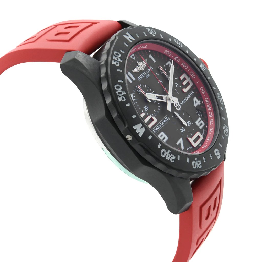 An image of a Breitling men's sport wristwatch in display model condition, shown from a side profile view opposite the crown, highlighting the round shape of the Breitlight case. The black dial and bezel are visible at an oblique angle, with the rubber band in focus, showing part of its red color and texture. The watch appears to be at a close distance, providing clear details of the timepiece's design. Can have minor blemishes on the watch during handling and shipping. 
