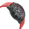 An image of a Breitling men's sport wristwatch in display model condition, shown from a side profile view opposite the crown, highlighting the round shape of the Breitlight case. The black dial and bezel are visible at an oblique angle, with the rubber band in focus, showing part of its red color and texture. The watch appears to be at a close distance, providing clear details of the timepiece's design. Can have minor blemishes on the watch during handling and shipping. 