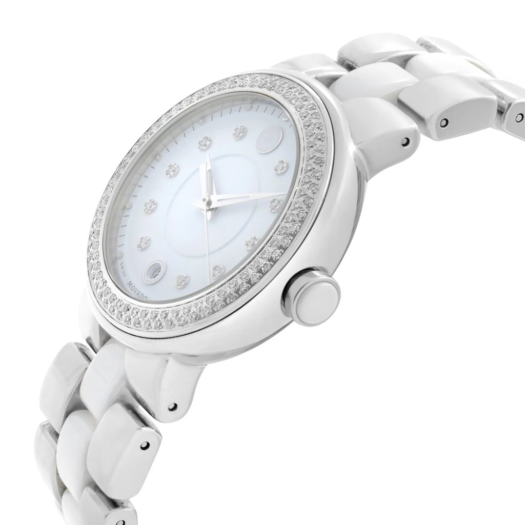 An image of a wristwatch viewed from the side profile, showcasing the crown prominently. The watch has a round face with a bezel adorned with small stones, and a metallic link band. The angle is slightly elevated, capturing the elegant design and pristine condition of this display model from a close distance.