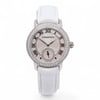 An image of a pre-owned Audemars Piguet Jules Diamond 18K White Gold Diamond Silver Dial Women's Watch 77228BC. The watch is positioned upright, facing directly towards the viewer, showcasing its round dial with Roman numerals and a small sub dial. The bezel is adorned with sparkling stones, and the watch is paired with a white leather strap. The photo is taken from a close-up angle, capturing the intricate details of the watch's face and strap.
