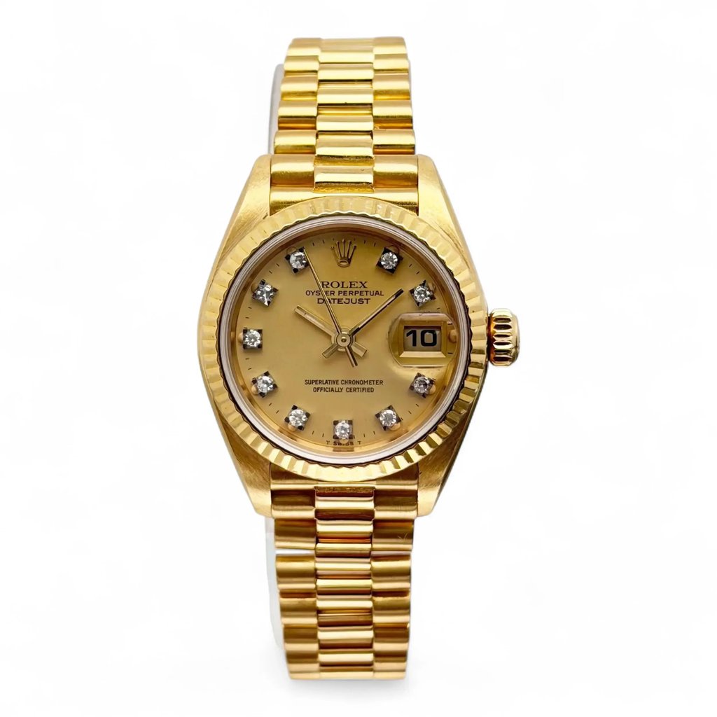 An image of a pre-owned women's Rolex President Datejust 26mm 18K Yellow Gold Champagne Diamond Dial Watch 69178, viewed from the front at a close distance. The watch is positioned vertically, showcasing its gold bracelet and a round dial. The dial features a date indicator and diamond hour markers. 